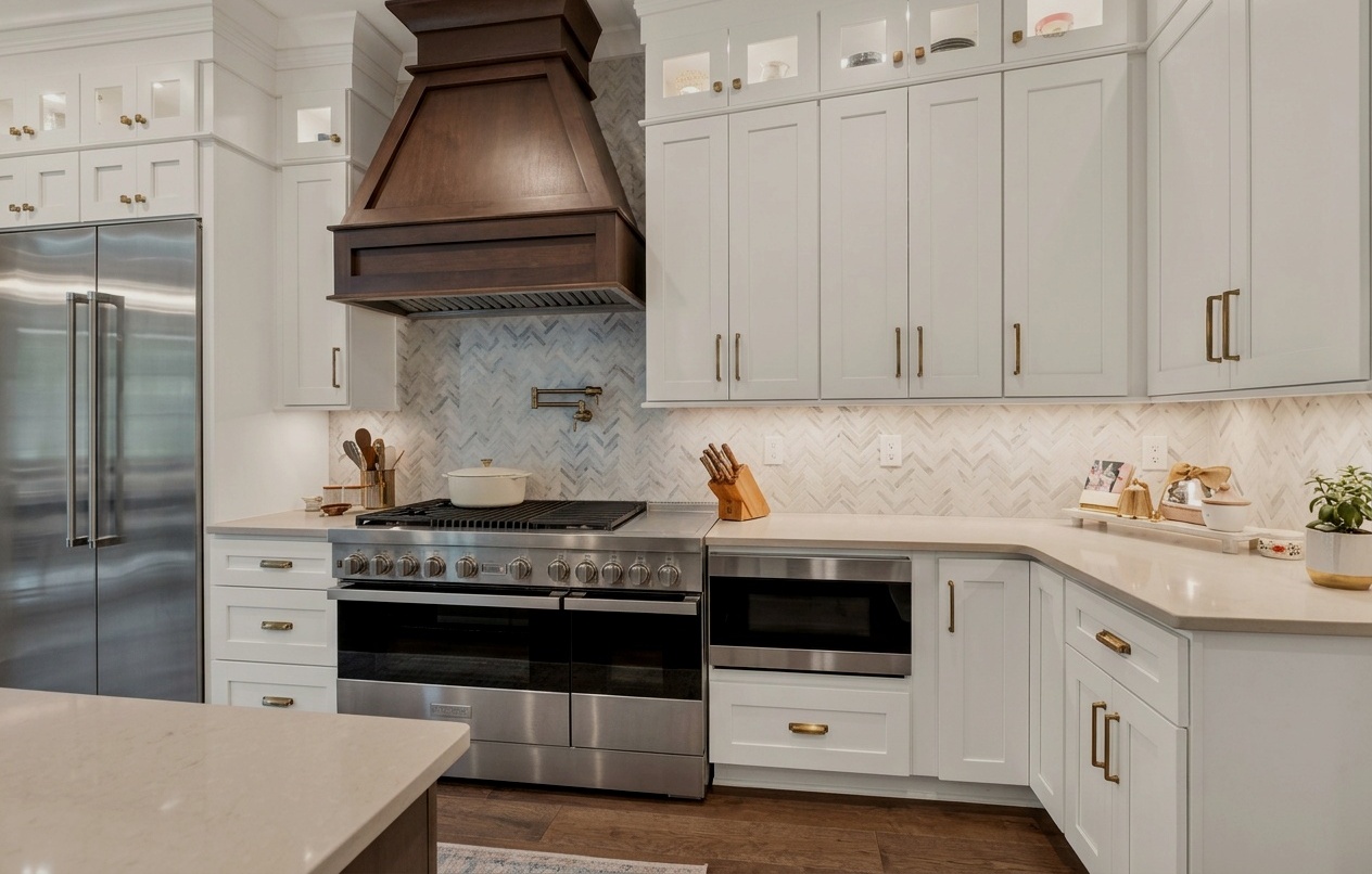 Custom white kitchen with dark wood range hood, marble island and gold hardware